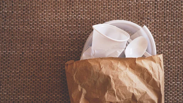 Beyaz plastik yemekleri bej renkli arka plan üzerinde bir kağıt paketindeki buruşuk — Stok fotoğraf