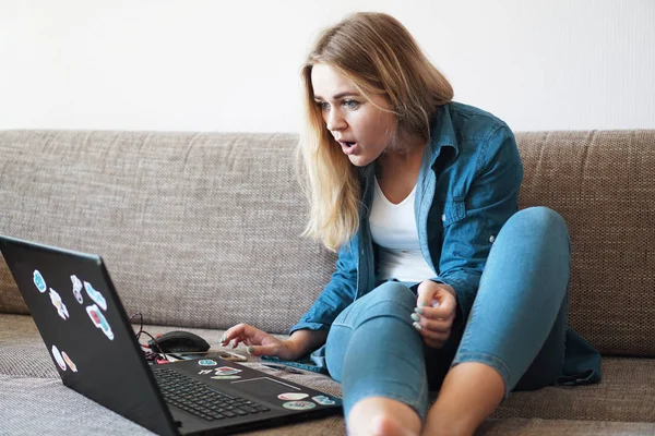 Schockierte junge Frau schaut auf Laptop-Bildschirm und sieht etwas Unglaubliches — Stockfoto