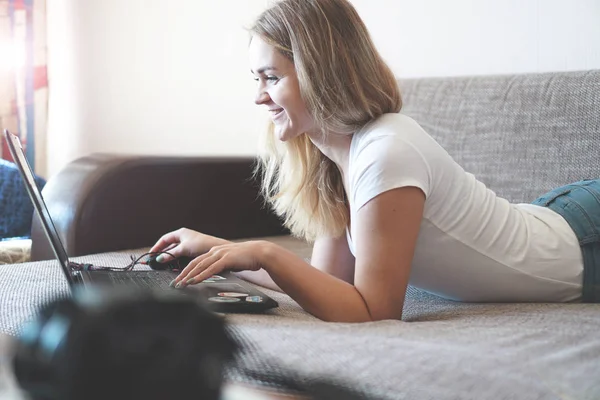 Mujer joven relajándose con un ordenador portátil en su sala de estar — Foto de Stock