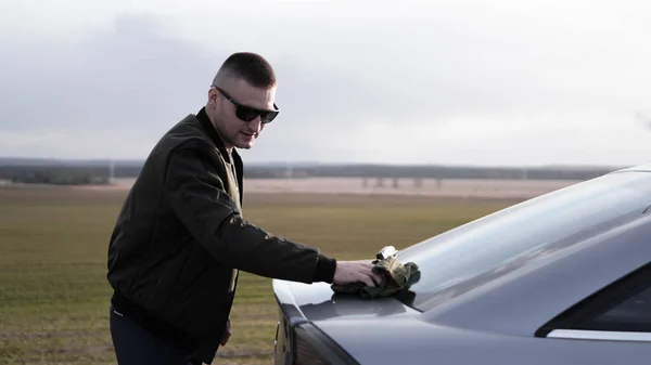 Shot van de jonge man die zijn auto met een doek oppoetsen — Stockfoto