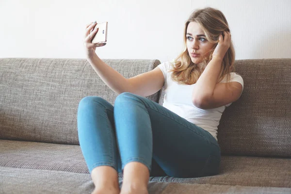Felice giovane donna prendendo selfie con il suo cellulare mentre seduto in soggiorno — Foto Stock