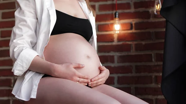 Беременная женщина держит руки за шишку — стоковое фото