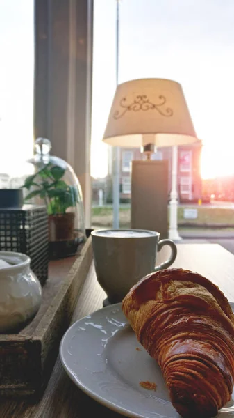 Šálek kávy a čerstvé pečené croissanty na desce ke snídani na stole — Stock fotografie
