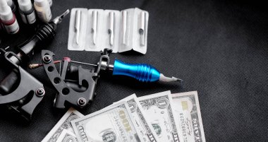 Tattoo machines on a black background and dollars. Tattoo art concept clipart