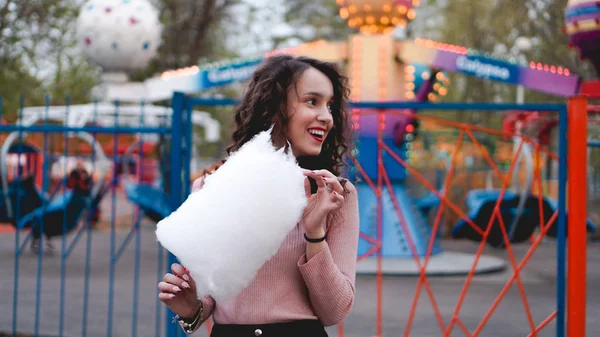 Ritratto di una sorridente ragazza eccitata che tiene lo zucchero filato al parco divertimenti — Foto Stock