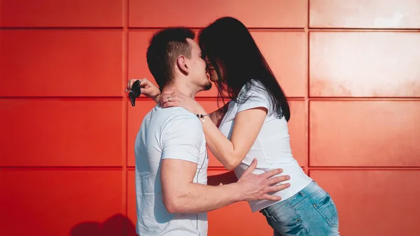Pareja besándose contra aislada pared roja en la ciudad — Foto de Stock