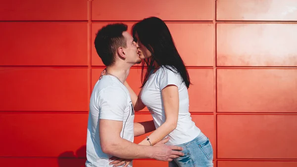 Pareja besándose contra aislada pared roja en la ciudad — Foto de Stock
