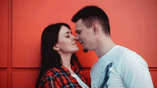 街の孤立した赤い壁にキスするカップル — ストック写真