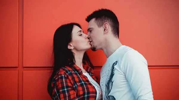 Pareja besándose contra aislada pared roja en la ciudad —  Fotos de Stock
