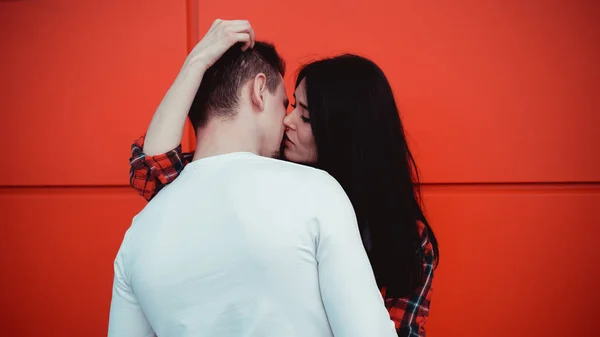 Casal beijando contra parede vermelha isolada na cidade — Fotografia de Stock