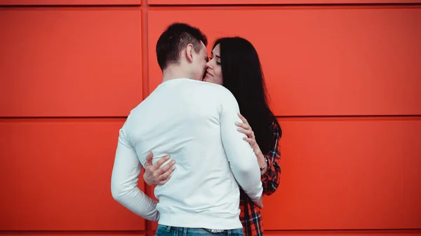 Pareja besándose contra aislada pared roja en la ciudad —  Fotos de Stock