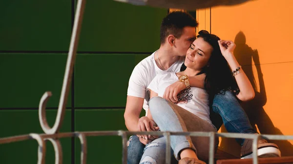 Пара поцелуев против изолированной желтой и зеленой стены в городе — стоковое фото