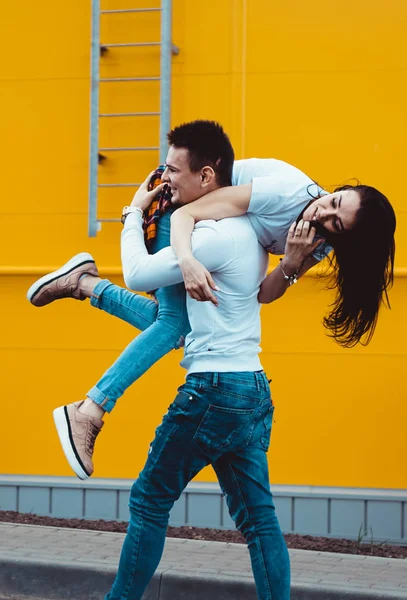 Feliz hombre llevando a su novia sobre fondo amarillo — Foto de Stock