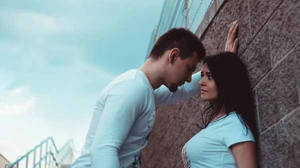 Jóvenes parejas amorosas de pie junto a la pared de ladrillo, felices y satisfechos —  Fotos de Stock