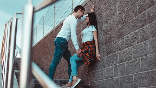 Jóvenes parejas amorosas de pie junto a la pared de ladrillo, felices y satisfechos —  Fotos de Stock