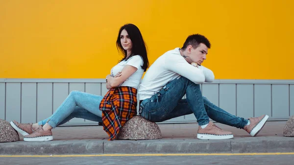 Confuso jovem casal de pé com um anothers volta sobre fundo amarelo — Fotografia de Stock