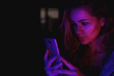 Neon ışık - pembe ve mavi ile gece cep telefonu kullanan kız