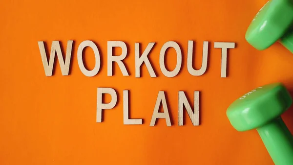 健身理念，锻炼计划。橙色背景上的绿色哑铃。顶部视图 — 图库照片