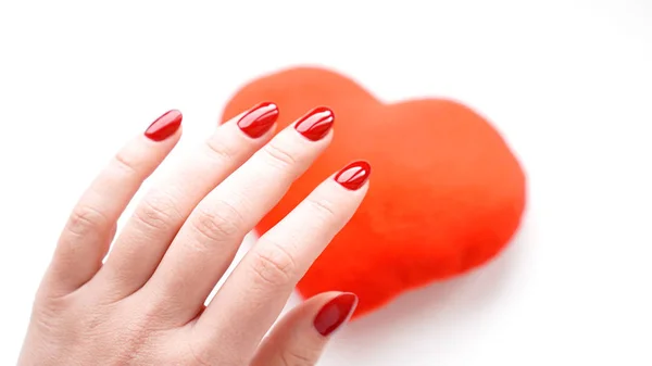 มือผู้หญิงที่มีหัวใจสีแดงแยกจากพื้นหลังสีขาว คอนเซปต์ แมนนิเคียร์ — ภาพถ่ายสต็อก