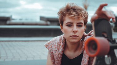 Güzel bir genç kız kaykay tutan bir kaykay sırasında kaykay