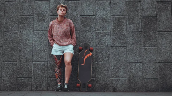 Beautiful young girl with tattoos with longboard