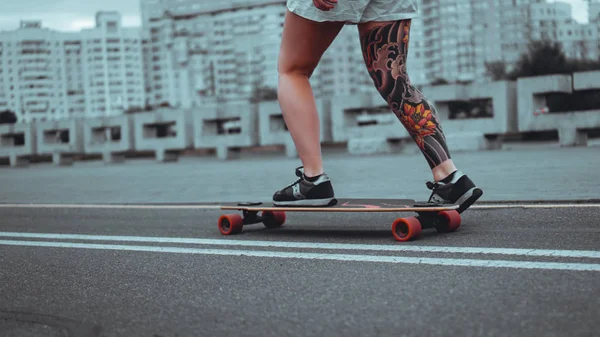 Beautiful young girl with tattoos with longboard