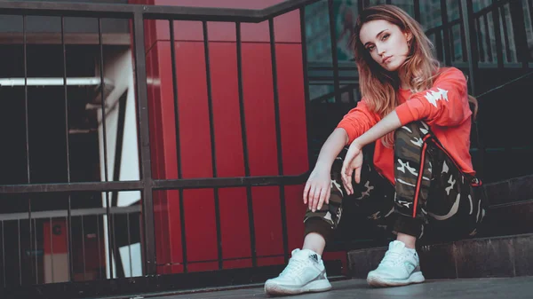 Modelo de moda vestindo capuz vermelho com inscrição los angeles posando no estacionamento — Fotografia de Stock