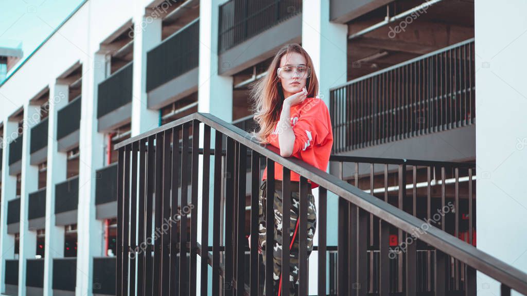 Fashion model wearing red hoodie with inscription los angeles posing at parking