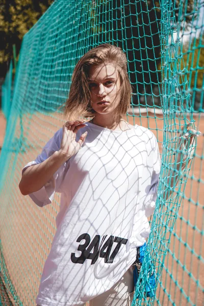 Mulher moderna elegante posa para uma foto em um campo de esportes no verão — Fotografia de Stock