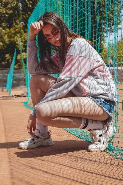 Mulher moderna elegante posa para uma foto em um campo de esportes no verão — Fotografia de Stock