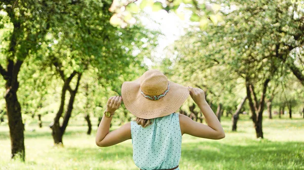 Giovane donna in cappello di paglia in giardino soleggiato — Foto Stock