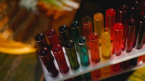 Tubos de ensayo con líquido multicolor. Alcohol en tubos de ensayo barra oscura —  Fotos de Stock
