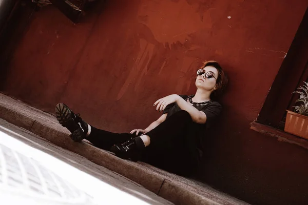Portrait d'une belle femme assise sur le sol au-dessus du mur rouge — Photo