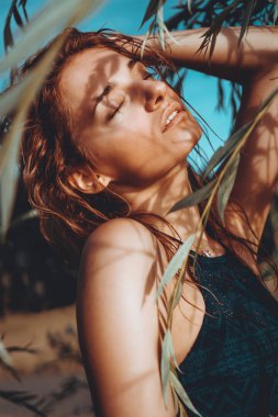 Bitkilerile tropikal bir plajda bikini kadın