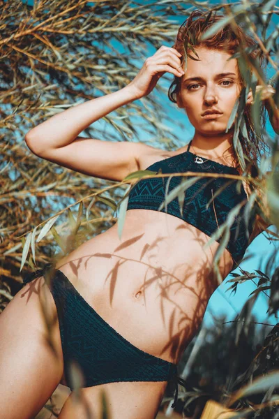 Kvinna i bikini på en tropisk strand med växter — Stockfoto