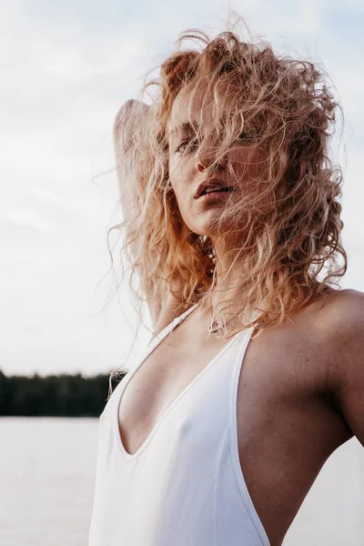 Όμορφη σέξι γυναίκα σε ένα λευκό μαγιό με μια ανοιχτή πλάτη που ποζάρει κοντά στη λίμνη, — Φωτογραφία Αρχείου