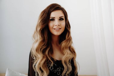 Güzel seksi kahverengi kıvırcık uzun saçlı kadın yatakta poz