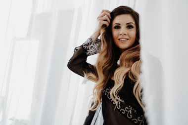 Güzel seksi kahverengi kıvırcık uzun saçlı kadın yatakta poz