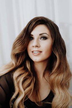 Güzel seksi kahverengi kıvırcık uzun saçlı kadın yatakta poz