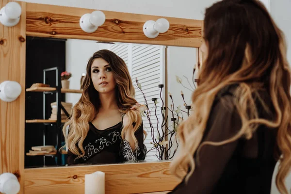 Hermosa mujer joven mirando su reflejo en un espejo del vestuario — Foto de Stock
