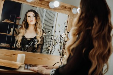 Güzel genç kadın bir soyunma odasında aynada yansıması bakarak