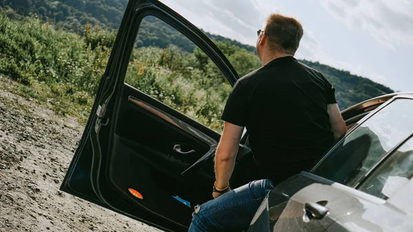 Achteraanzicht van een man die op een berg uitzicht staat. Reiziger geniet van landschap — Stockfoto