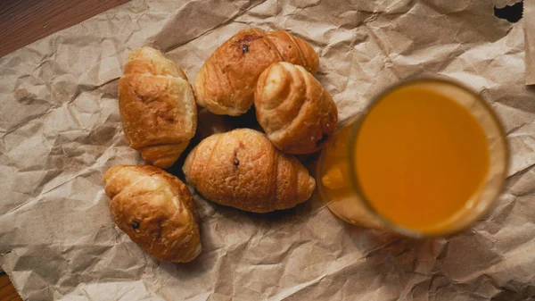 Croissants recién horneados con jugo de naranja sobre papel kraft. Delicioso postre —  Fotos de Stock