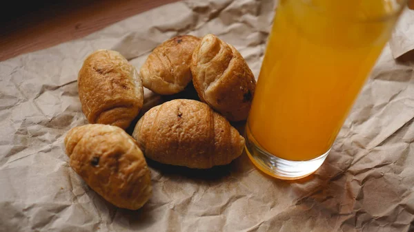 Croissants recién horneados con jugo de naranja sobre papel kraft. Delicioso postre —  Fotos de Stock