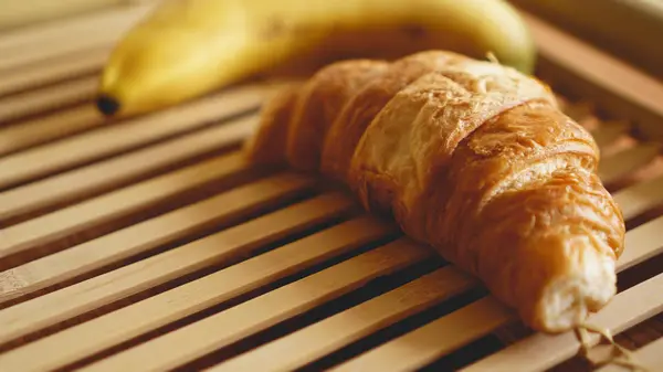 Plátano y croissant sobre fondo rústico de madera. Enfoque selectivo, horizontal —  Fotos de Stock