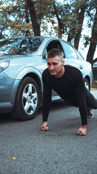 Knappe man in de buurt van de auto. De atleet wrat uit naast de machine — Stockfoto