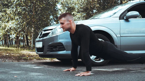 Knappe man in de buurt van de auto. De atleet wrat uit naast de machine — Stockfoto