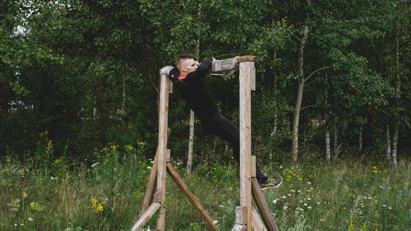 Hombre pasando por obstáculos durante la carrera de obstáculos en el campo de entrenamiento — Foto de Stock