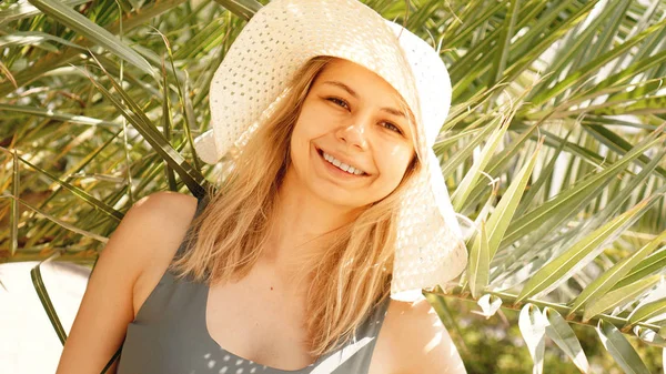 Frau mit Hut unter Palmen entspannt. Sommerurlaub oder Urlaub. — Stockfoto