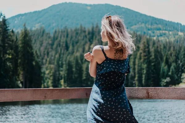 Smiling woman against mountain landscape and lake